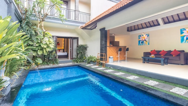 A swimming pool with a patio area, a sofa set, and a painting on the wall. - Cozzy Dewa Villa Sunset Road (Badung)