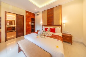 Ein Hotelzimmer mit einem großen Bett, einem Holzschrank, einem Nachttisch und einem durch eine geöffnete Tür einsehbaren Badezimmer.