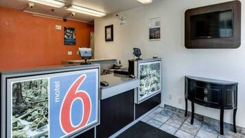 A motel lobby with reception desks, a TV, and a sign indicating the motel number.