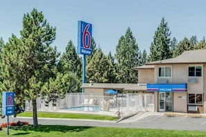 Un motel con piscina, área cercada y un letrero de 'Welcome'.
