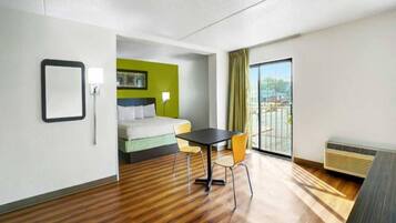 A hotel room with a bed, a table, chairs, a window with a view, and a radiator.