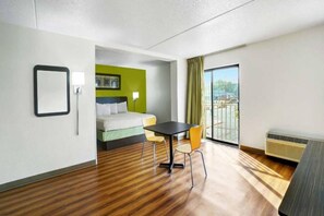 A hotel room with a bed, a table, chairs, a window with a view, and a radiator. - 1 King Bed | Smoking, Micfridge (Lawrenceville)