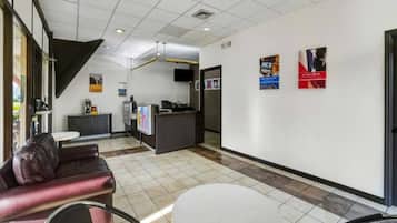 A lobby with a reception desk, seating area, and a staircase.