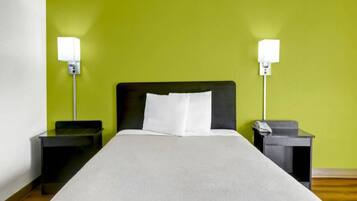 Una habitación de hotel con una cama, dos mesitas de noche y lámparas de noche.