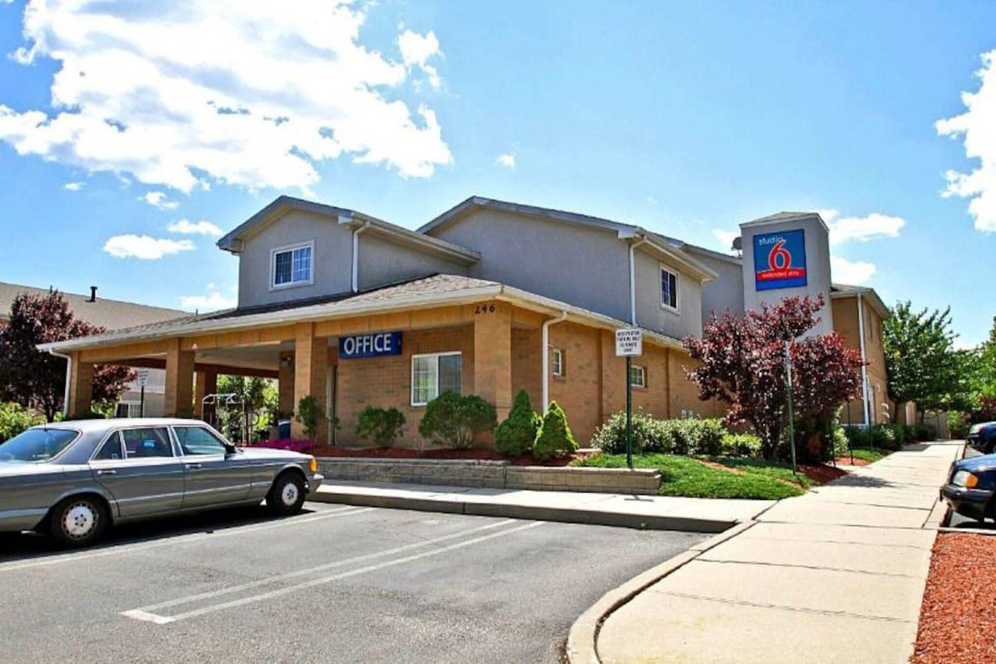 A building with an 'OFFICE' sign, a parking lot, and a '6' sign indicating a nearby location.
