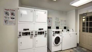 A laundry facility with stacked dryers and a front-loading washing machine.