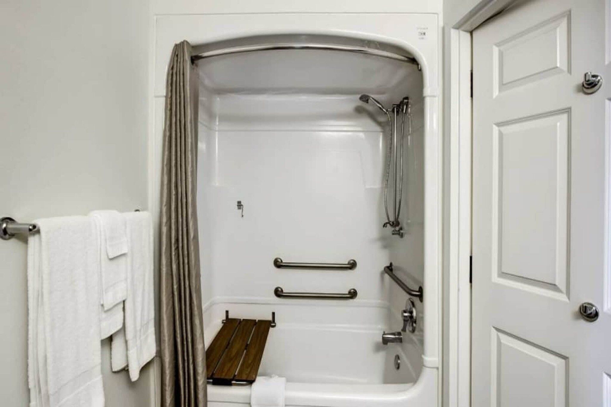 Une salle de bain équipée d’une douche, de barres d’appui et d’un porte-serviettes.
