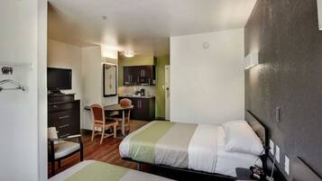 Una habitación de hotel con dos camas, un escritorio, una silla y una kitchenette.