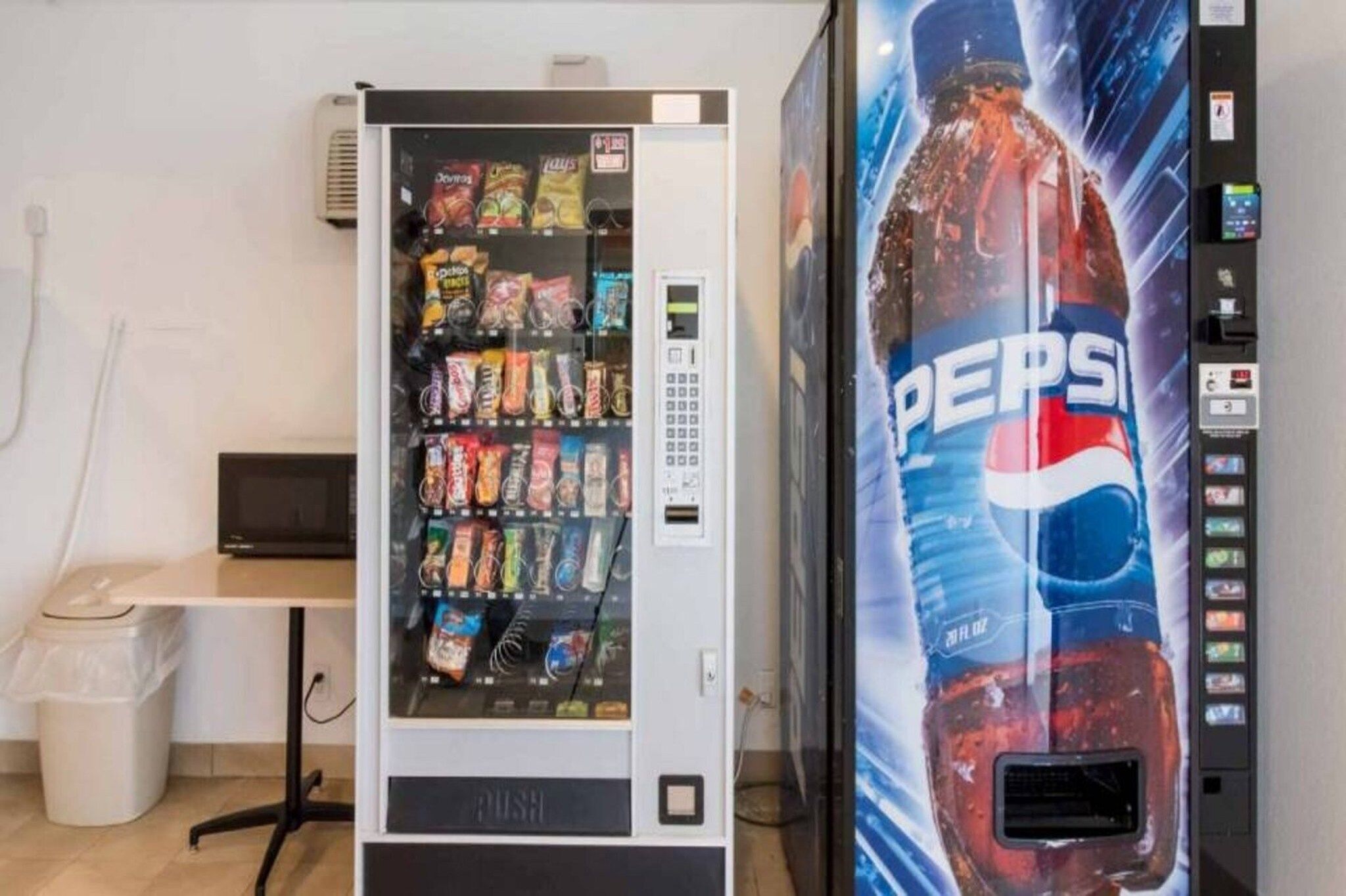 A vending machine stocked with snacks and a large Pepsi advertisement.