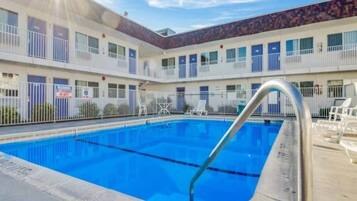 Um hotel com piscina, várias varandas e área cercada.