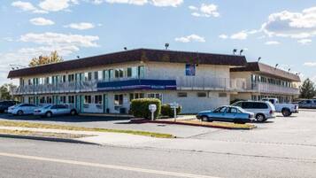 A motel with a parking lot, a 'Welcome' sign, and a '6' sign indicating the number of rooms.