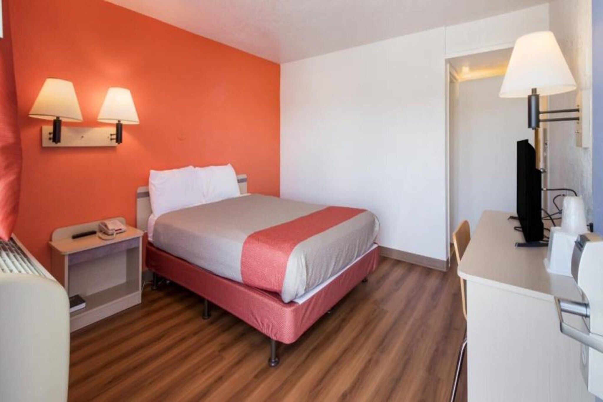 A hotel room with a bed, bedside tables, a desk, and a chair.