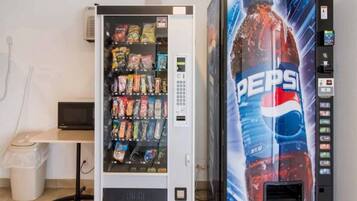 A vending machine stocked with snacks and a large Pepsi advertisement.