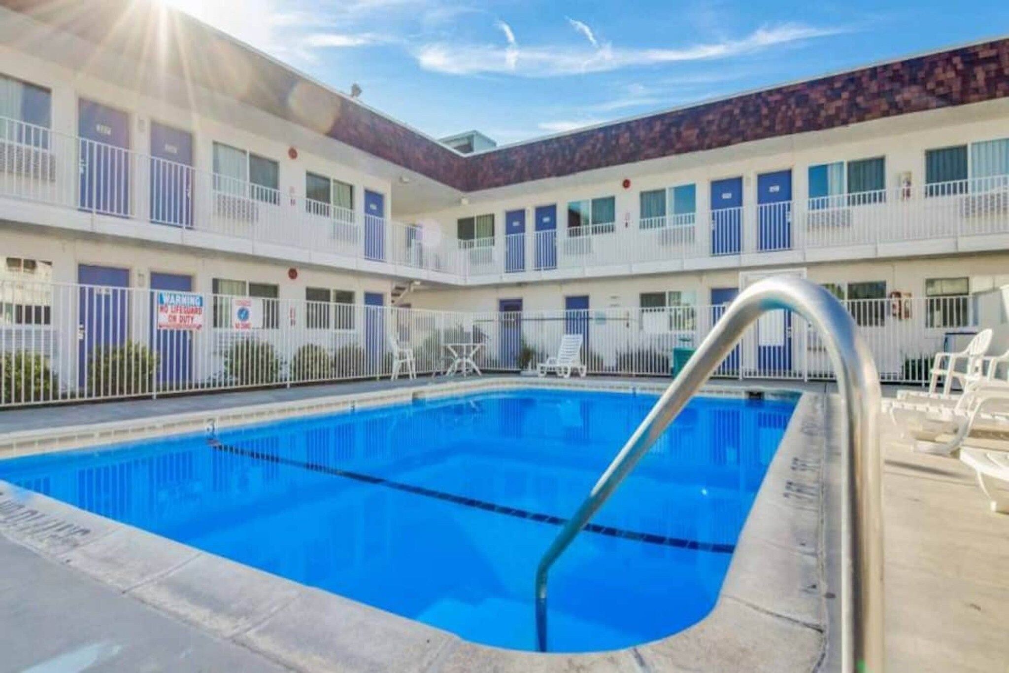 Hotel com piscina, várias varandas e área cercada.