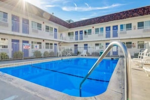 A hotel with a swimming pool, multiple balconies, and a fenced area.