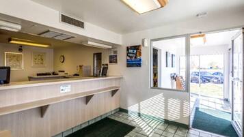A reception area with a counter, a clock, and a door leading outside.