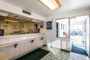 Un'area reception con un banco, una sveglia e una porta che dà sull'esterno.