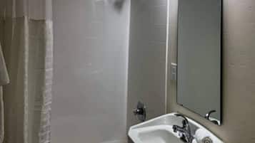 A bathroom with a shower, a sink, and a mirror.