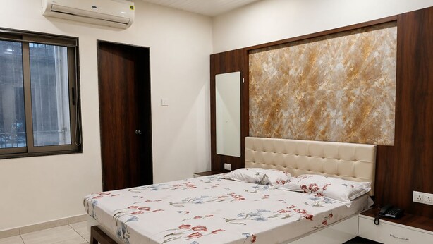 Un dormitorio con cama, ventana, equipo de aire acondicionado, puerta de madera y pared con diseño de mármol.