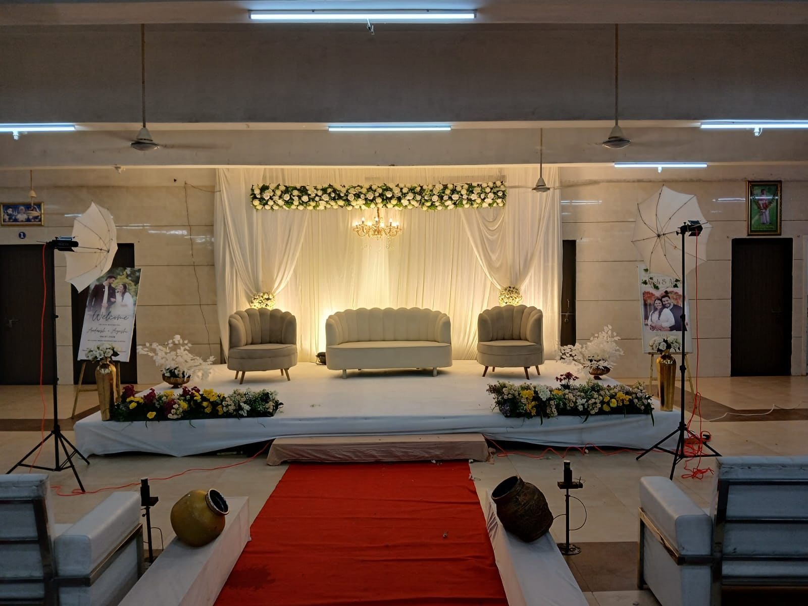 Un escenario con tres sofás, una alfombra roja y arreglos florales.