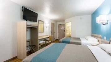 A hotel room with two beds, a TV, a desk, and a wardrobe.