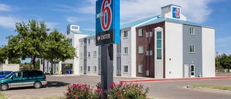 A motel with a prominent '6' sign, a parking area, and a building with multiple windows.