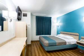 A hotel room with a bed, bedside table, a desk, a chair, a TV, and a window with curtains. - Spacious ADA Queen Bed|Free Wifi (Roswell)
