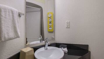 A bathroom with a white sink, a mirror, a towel rack, and a yellow soap dispenser.