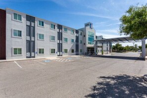 A modern building with a parking lot and a covered entrance area.