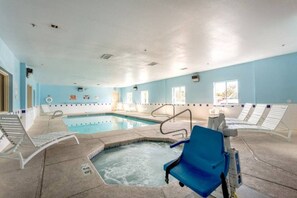 Une piscine intérieure dotée d’un jacuzzi, de chaises longues et d’un plafond transparent.