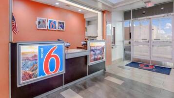 A hotel reception area with a large '6' sign, a reception desk, and a glass door entrance.