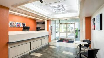 A reception area with a counter, chairs, and a glass door leading outside.