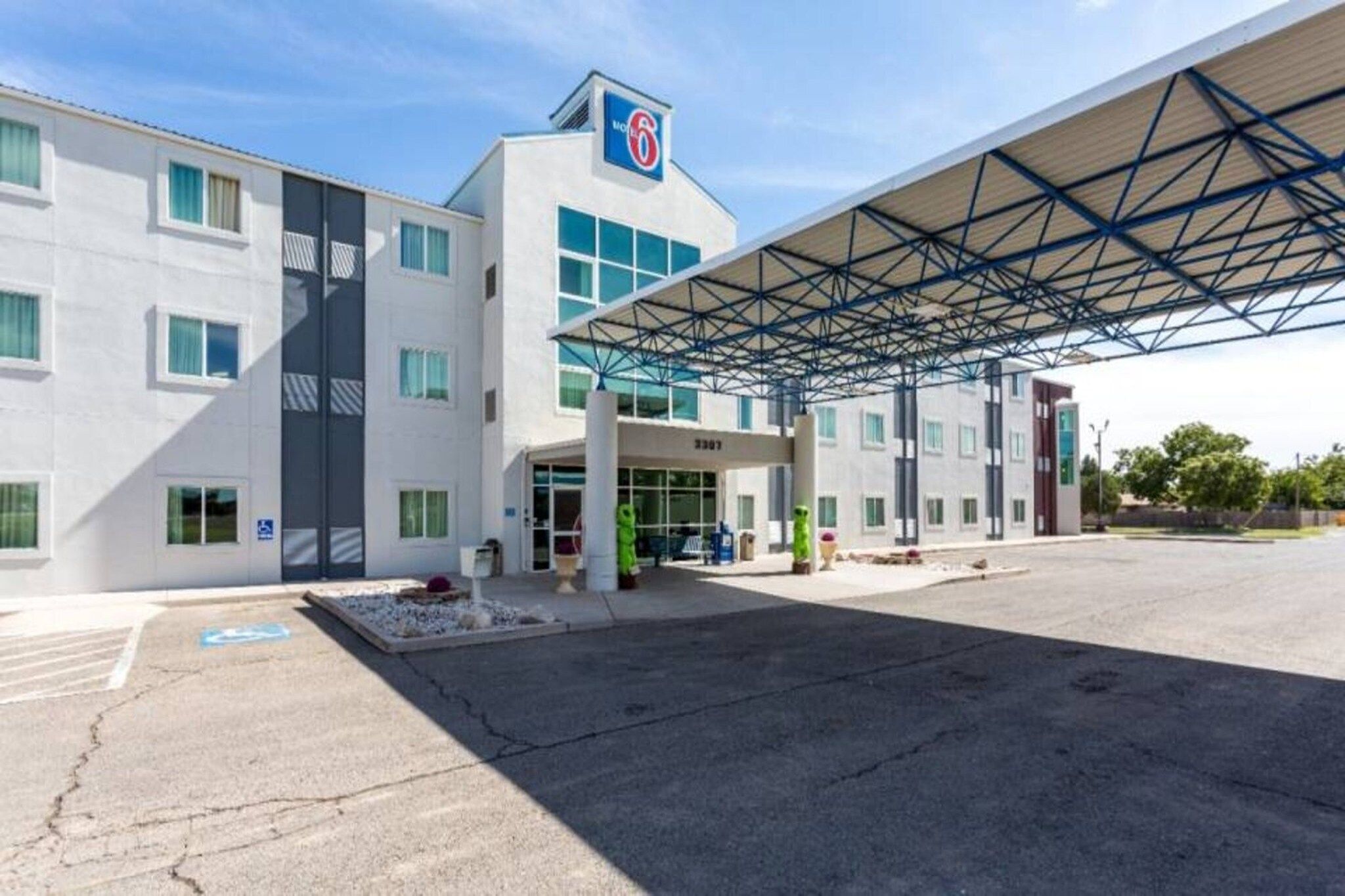 A modern building with a covered entrance, multiple windows, and a visible parking area.