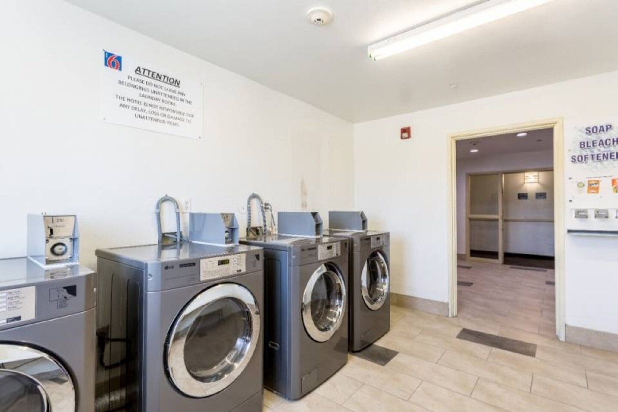 A laundry facility with multiple washing machines and a sign indicating the importance of not leaving laundry unattended.