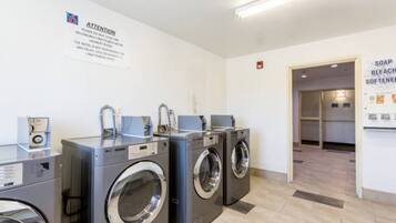 A laundry facility with multiple washing machines and a sign indicating the importance of not leaving laundry unattended.