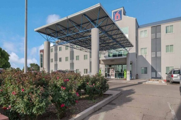 A hotel with a covered entrance, a six-story building, and a parking area.