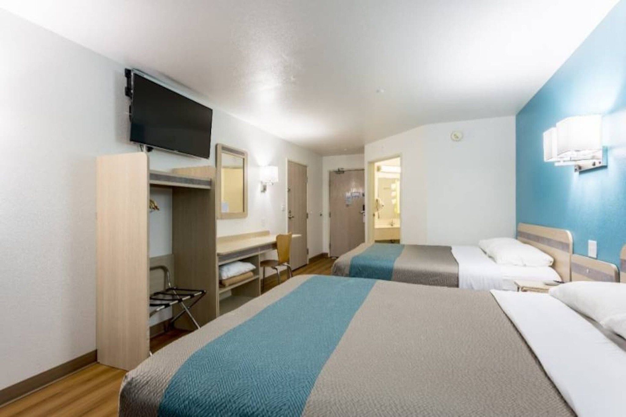 A hotel room with two beds, a TV, a desk, and a chair.