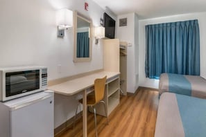 A hotel room with a bed, a desk, a chair, a television, and a microwave.