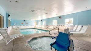 An indoor swimming pool with a hot tub, lounge chairs, and a clear ceiling. - Spacious 2-Bed|Free Parking|Wifi (Roswell)