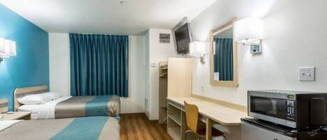A hotel room with two beds, a desk, a chair, a microwave, and a television.