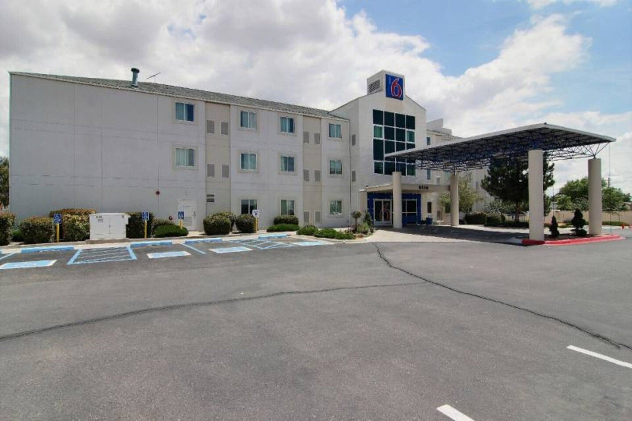 A large building with a parking lot, a covered entrance, and a sign with the number 6.