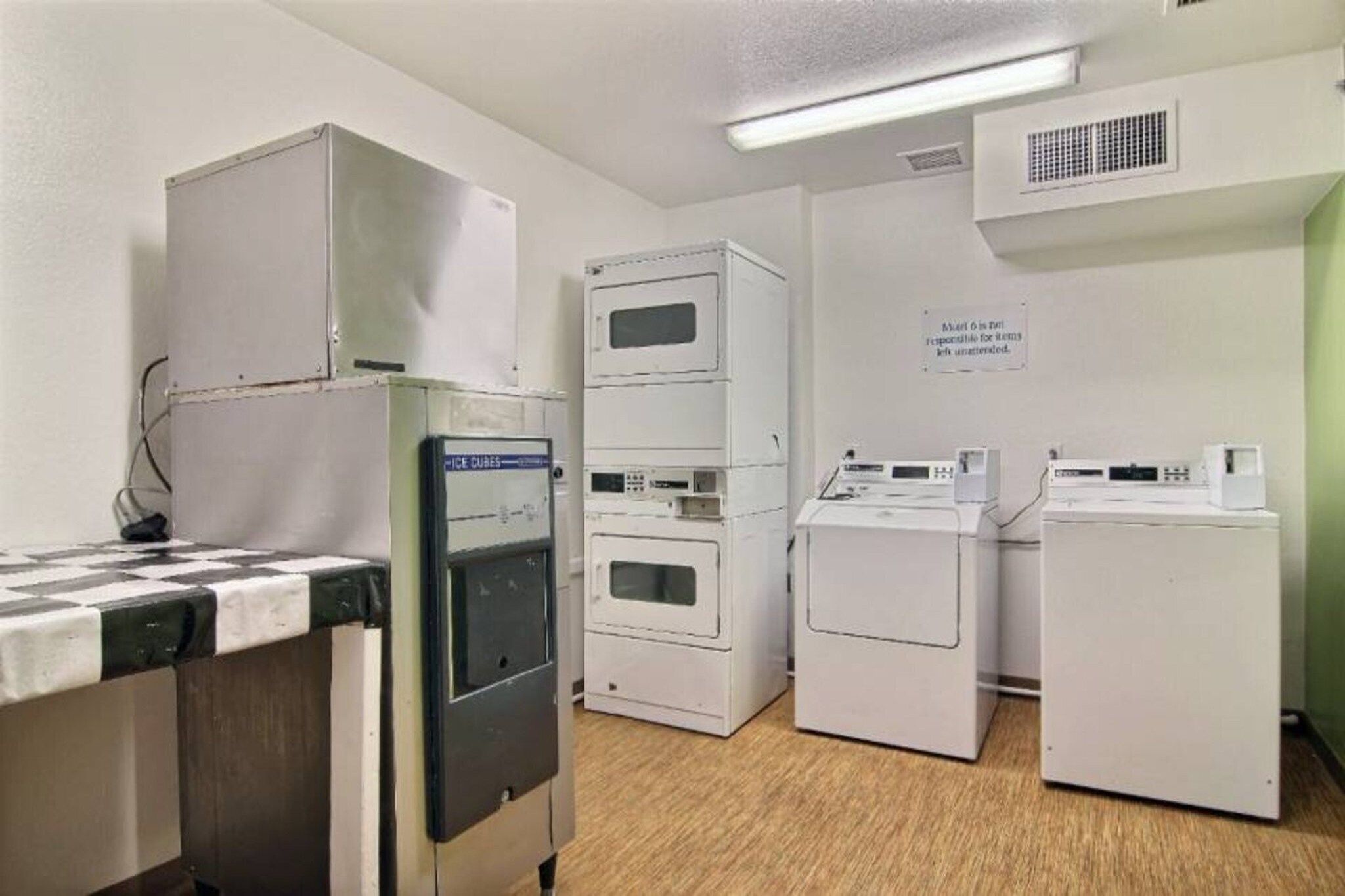 A laundry room with stacked dryers, a washing machine, and a refrigerator.