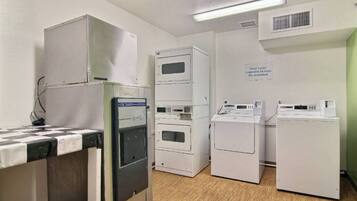 A laundry room with stacked dryers, a washing machine, and a refrigerator.