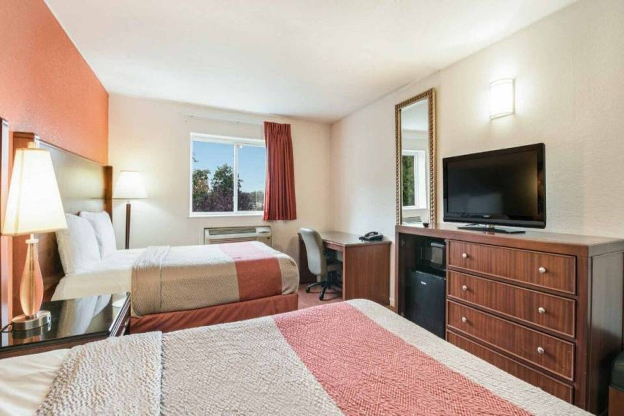 Quarto de hotel com duas camas, uma escrivaninha, uma televisão e um armário.