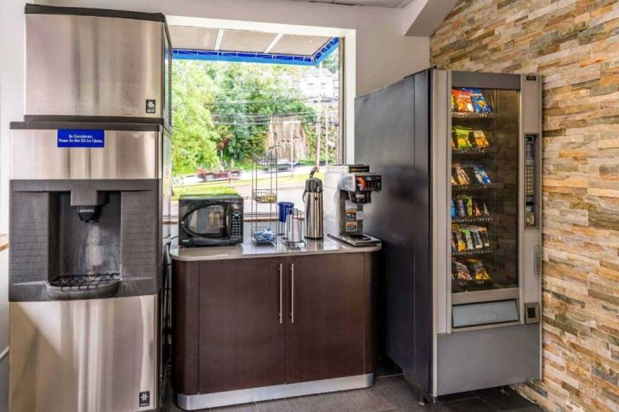 A kitchenette with a water dispenser, microwave, coffee machine, and a snack vending machine.