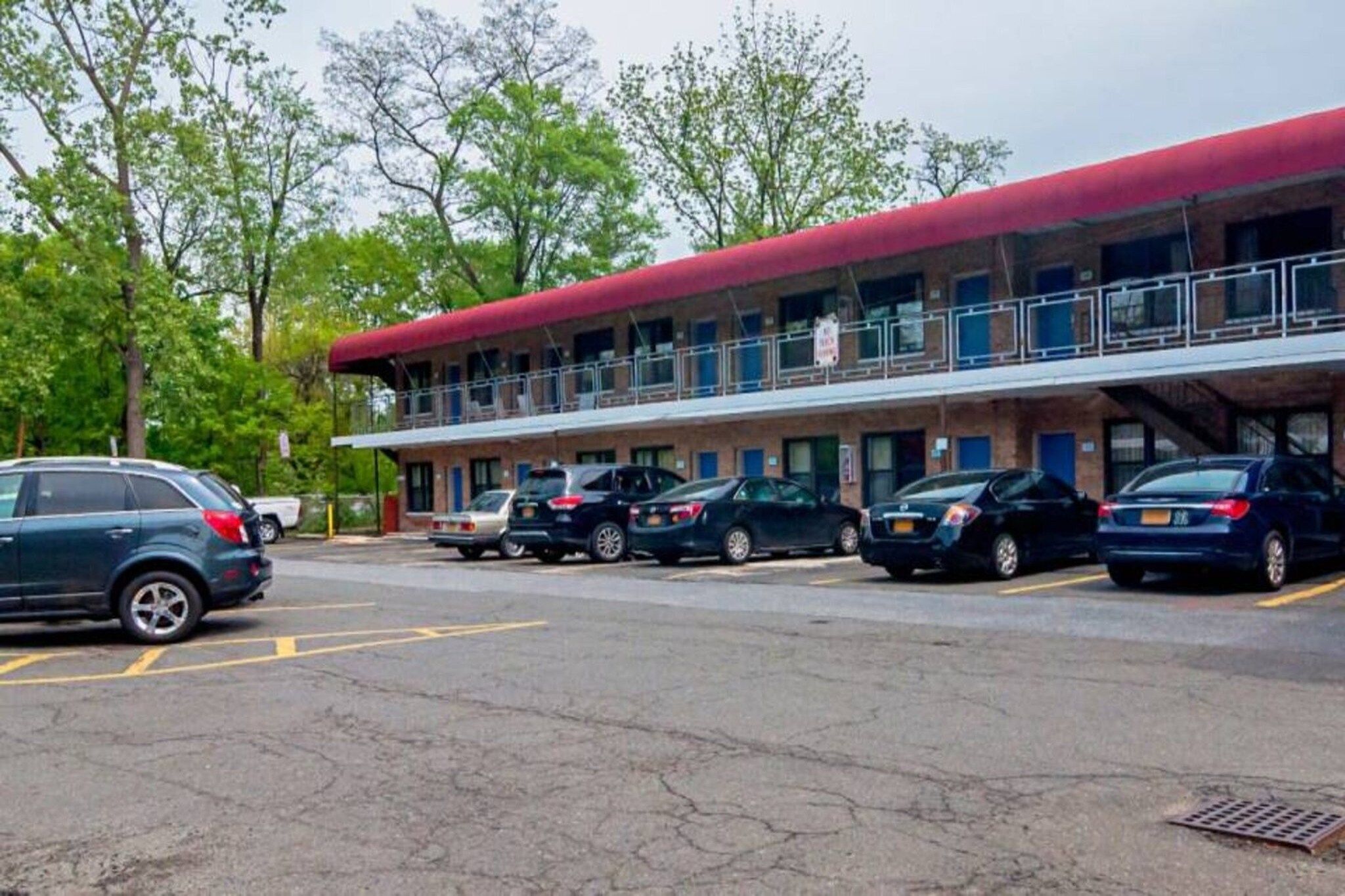 A motel with a red roof and a covered parking area.