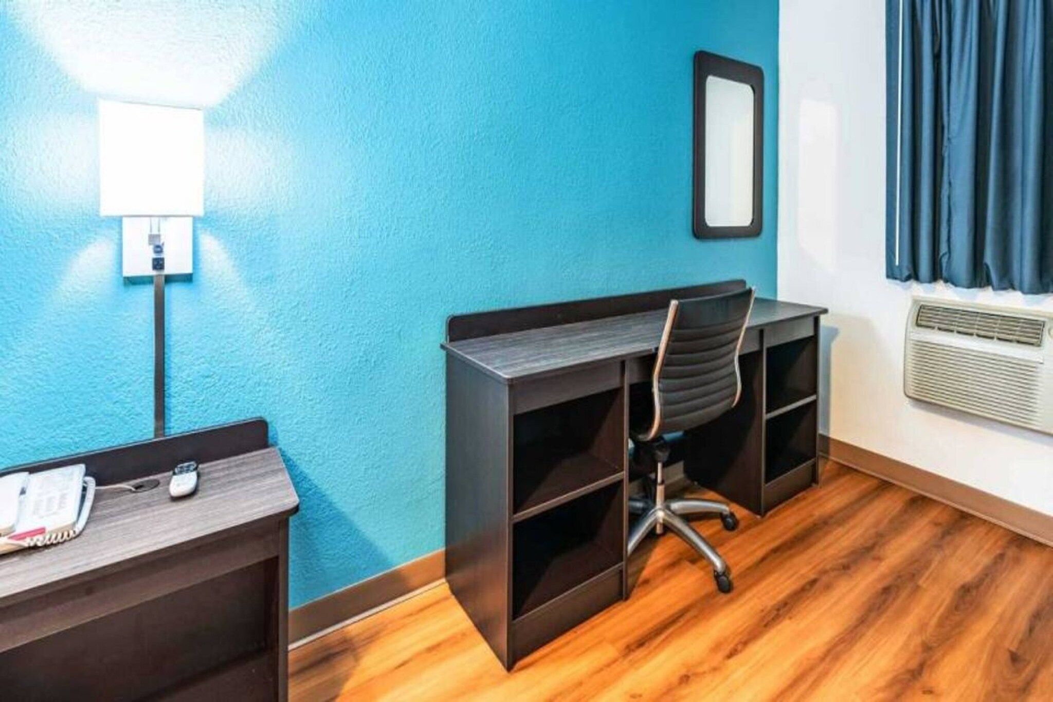 A room with a desk, chair, and a wall-mounted light fixture.