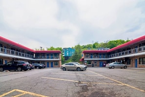 A parking lot with multiple cars, a building with a red roof, and a blue building in the background.