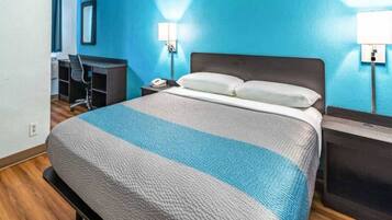 A hotel room with a bed, a desk, and a chair.