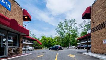 A parking lot with cars, a building with a red awning, and a clear sky.